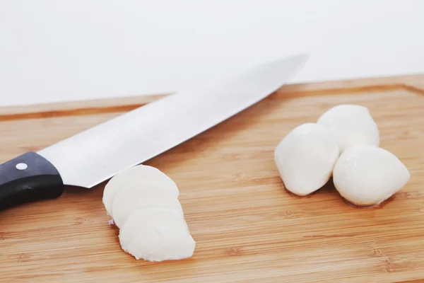 Sliced mozzarella with knife on wooden board — Stock Photo, Image