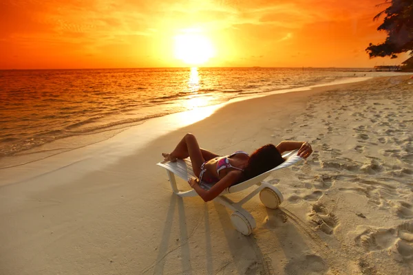 Woman in chaise-lounge relaxing on beach — Stock Photo, Image