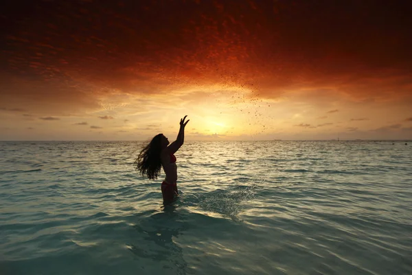 Mujer salpicando en el mar al atardecer Imagen De Stock
