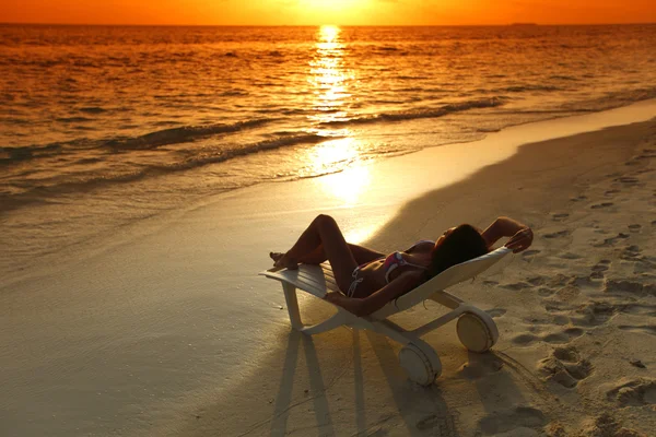 Mulher em chaise-lounge relaxante na praia — Fotografia de Stock