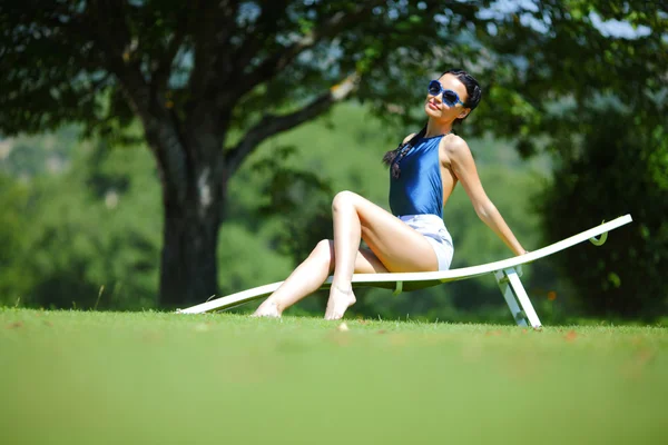 Dziewczyna siedzi w białym salonie na zielonej trawie — Zdjęcie stockowe