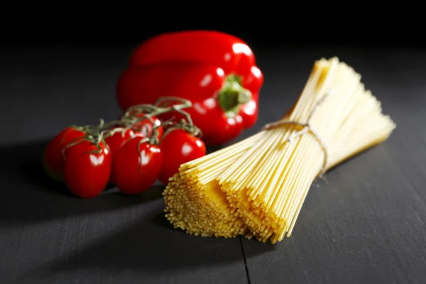 Raw pasta and vegetables on black table — Stock Photo, Image