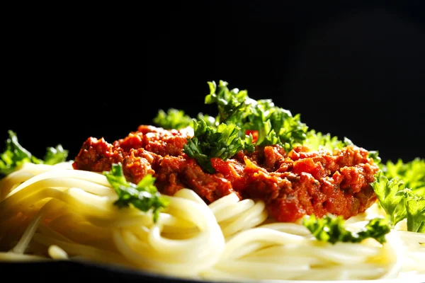 Spaghetti bolognese in black plate — Stock Photo, Image