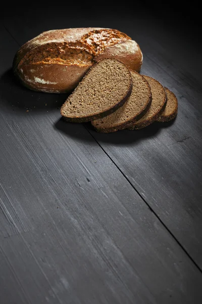 Sliced black bread on wooden table — Stock Photo, Image