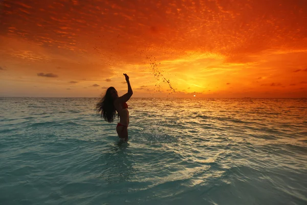 Vrouw spetteren in zee op zonsondergang — Stockfoto
