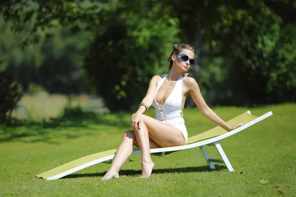 Chica sentada en un salón blanco sobre una hierba verde —  Fotos de Stock