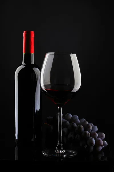 Flaske med rødvin og glas og druer - Stock-foto