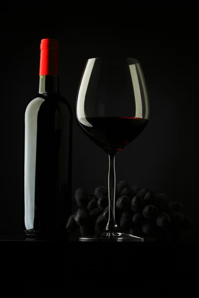 Botella con vino tinto y vidrio y uvas — Foto de Stock