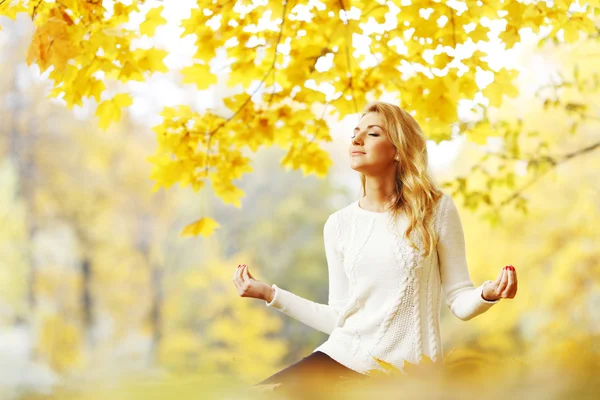 Женщина медитирует в осеннем парке — стоковое фото