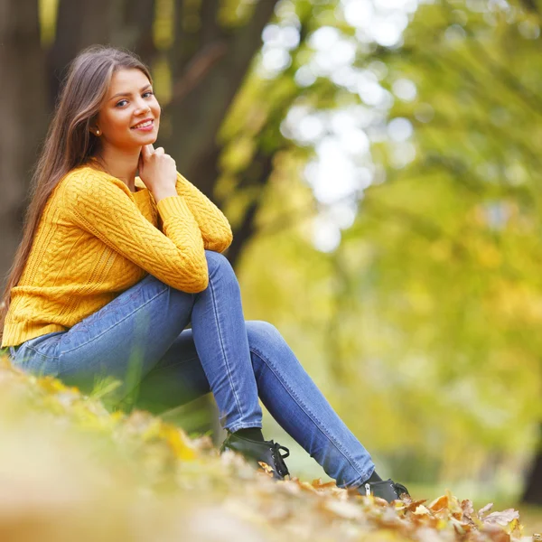 Mulher sentada nas folhas de outono — Fotografia de Stock