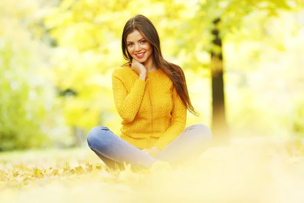 Donna seduta sulle foglie d'autunno — Foto Stock