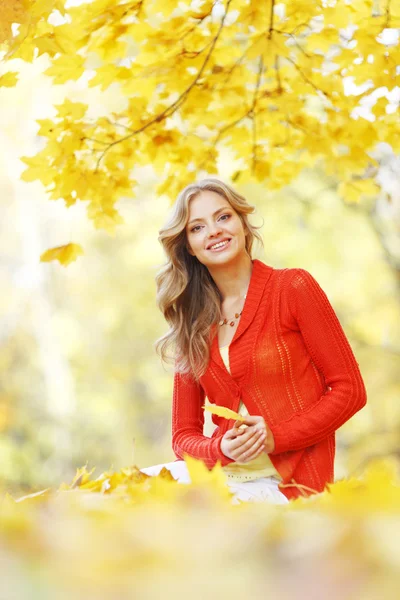 Sonbahar yaprakları üzerine oturan kadın — Stok fotoğraf