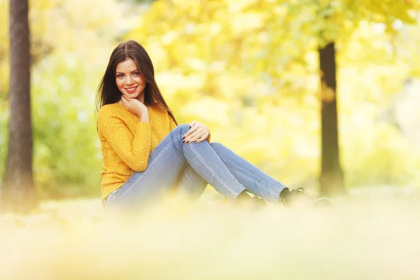 女子坐在秋天的树叶 — 图库照片