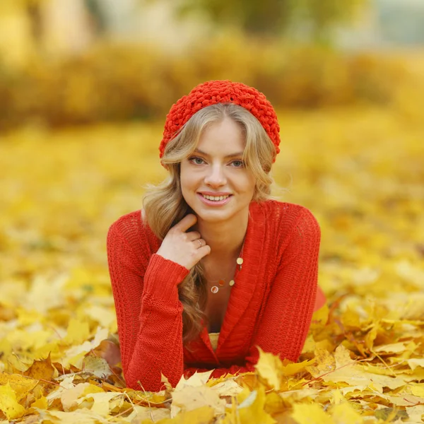 Mulher que põe em folhas de outono — Fotografia de Stock