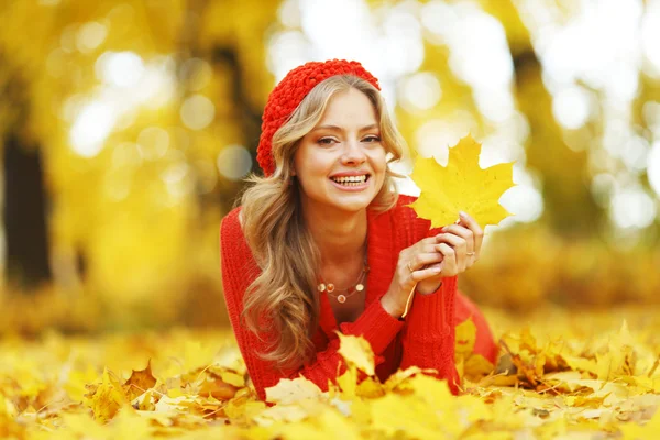 Mulher que põe em folhas de outono — Fotografia de Stock
