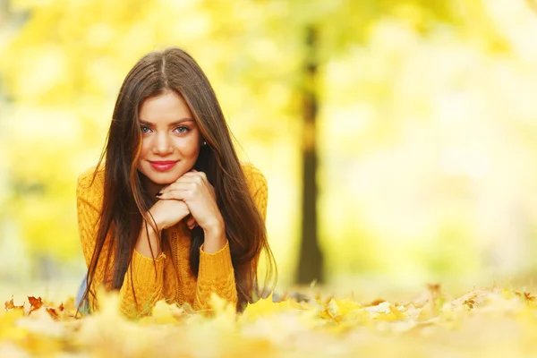 Menina que põe em folhas de outono — Fotografia de Stock