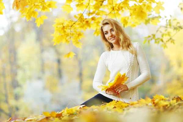 Žena sedí na podzimní listí — Stock fotografie