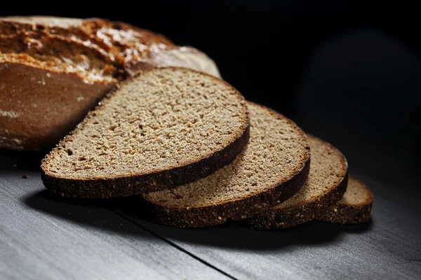 Szeletelt fekete kenyeret, a fából készült asztal — Stock Fotó