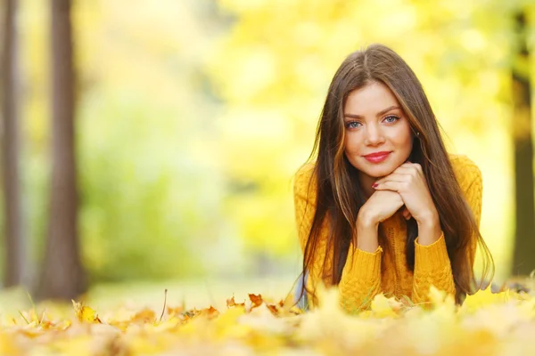 Menina que põe em folhas de outono — Fotografia de Stock