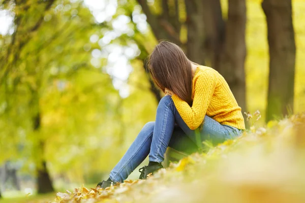 Donna seduta sulle foglie d'autunno — Foto Stock