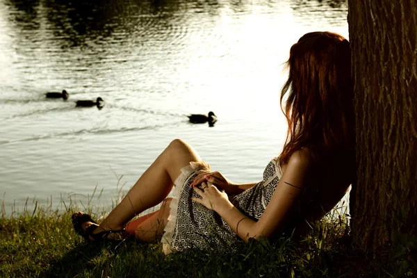 Dziewczyna siedzi na brzegu tha rzeki lasu — Zdjęcie stockowe