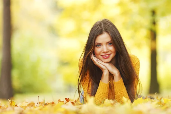 Menina que põe em folhas de outono Fotografia De Stock