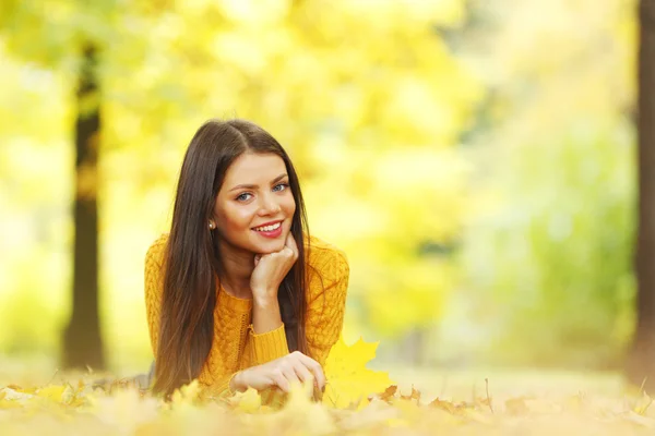 Yapraklar sonbaharda döşeme kız — Stok fotoğraf