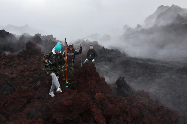 Tourists hiking on lava field eruption active Tolbachik Volcano on Kamchatka Peninsula. Russia