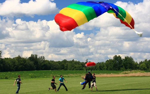 Skydivers in tandem jump just before land. Security team is around to help. — Stock Photo, Image