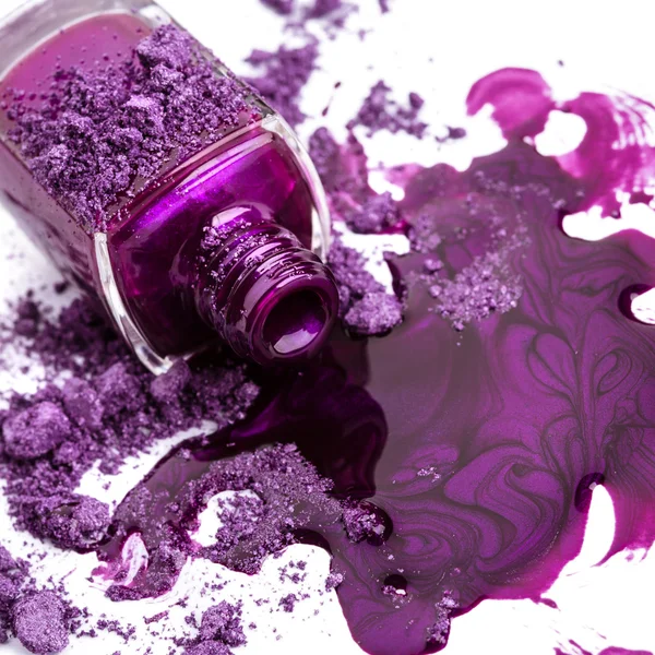 Фиолетовый лак для ногтей и раздробленные тени для глаз на белом фоне — стоковое фото