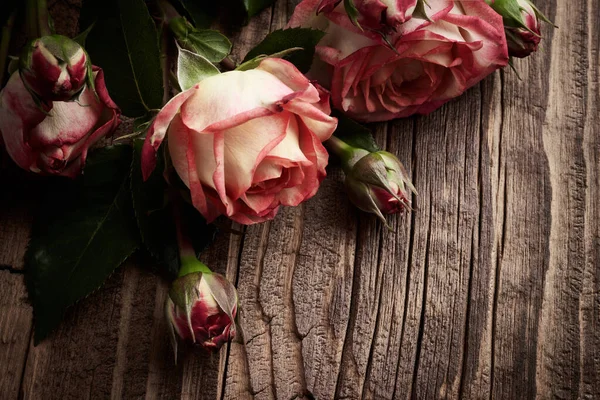 ヴィンテージの木の板の上にバラのいくつかの花の背景 — ストック写真