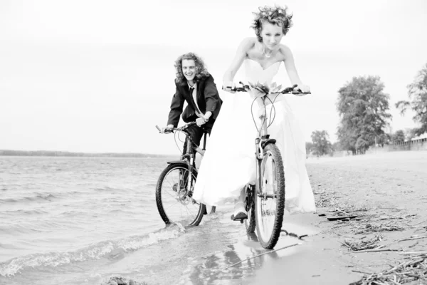 Happy bride and groom rides on bicycles Stock Picture
