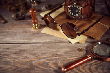 Steampunk hala hayatta. Ahşap bir arka planda eski nesneler. Deri kol saati, koyu gözlükler, eski lambalar, büyüteç, vites.