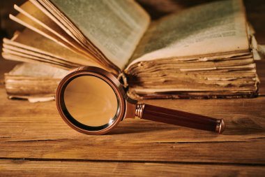 Büyüteç ve ahşap masadaki antik büyü kitabı.