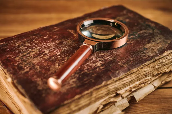 ガラスを拡大し 木製のテーブルの上に古代の魔法の本 — ストック写真