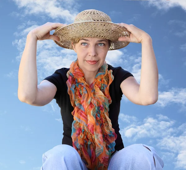 Uma mulher em um chapéu em um céu de fundo olha longe — Fotografia de Stock
