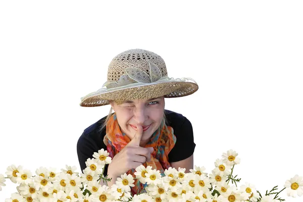 A woman in a hat shows quietly and winks in camomiles — Stock Photo, Image