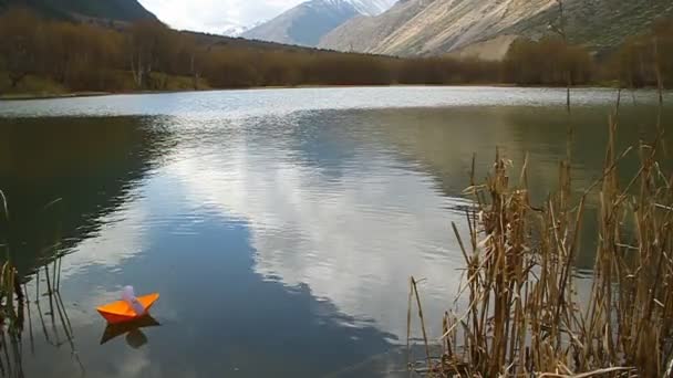 Oranje papier boot drijvend in bergmeer — Stockvideo