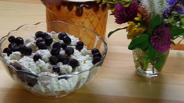 Blueberries stirred with a spoon with cottage cheese in a bowl on a wooden table — Stock Video