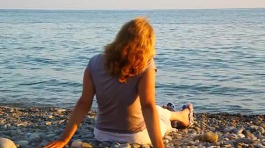 Sahilde deniz kenarında oturan bir kadın ve hayran zevk