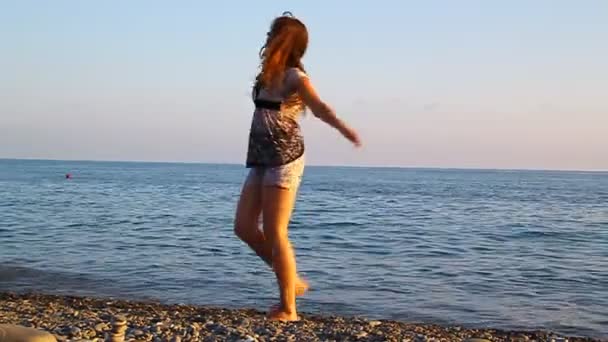 Молода красива дівчина крутиться на пляжі біля моря — стокове відео