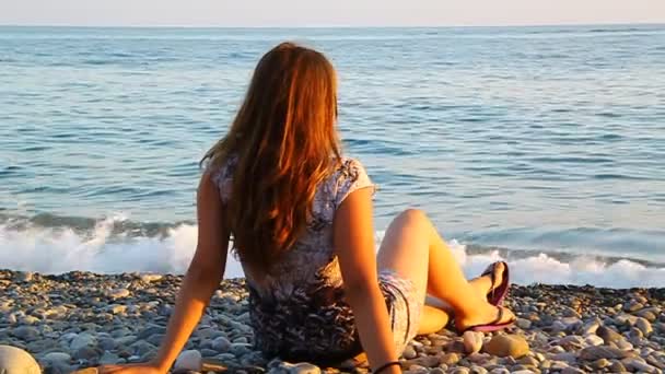 Jovem menina bonita admirando o mar ao pôr do sol — Vídeo de Stock