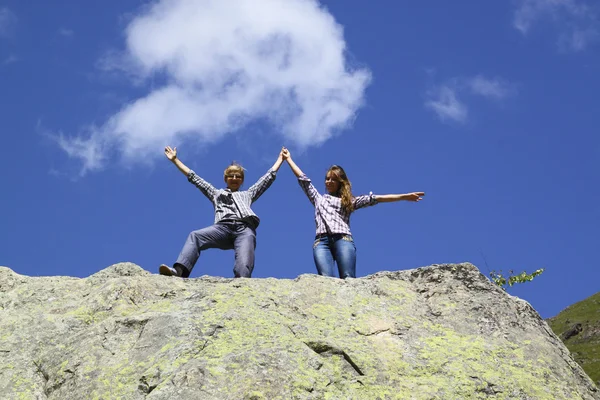 Happy mother and daughter standing on a huge rock, raising his hands up — Stock Photo, Image