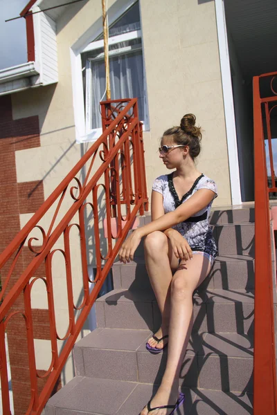 Jovem menina bonita sentada nos degraus da casa — Fotografia de Stock