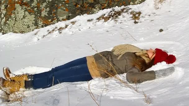 Молода щаслива дівчина лежить у снігу — стокове відео