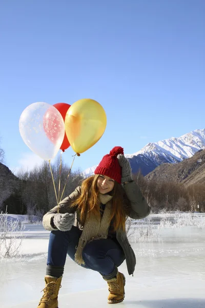 Menina feliz com balões no gelo contra o fundo do sn — Fotografia de Stock