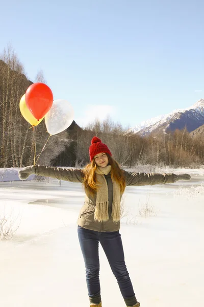 Happy girl with balloons on the ice against the background of sn — Stock Photo, Image