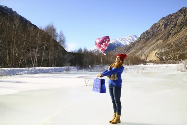 Menina feliz com um balão e um pacote com um presente no backg — Fotografia de Stock