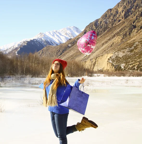 Chica feliz con un globo y un paquete con un regalo en la espalda —  Fotos de Stock