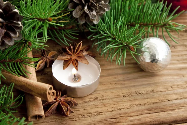 Decoración navideña con vela, abeto y canela sobre fondo de madera —  Fotos de Stock